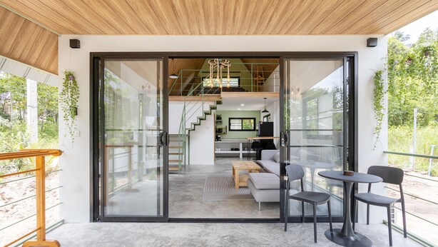 A modern interior with a glass door leading to a kitchen, a dining area with a table and chairs, and a staircase to an upper level. - Coconut WayWay Retreat by Sea N' Rent (Ko Pha-ngan)