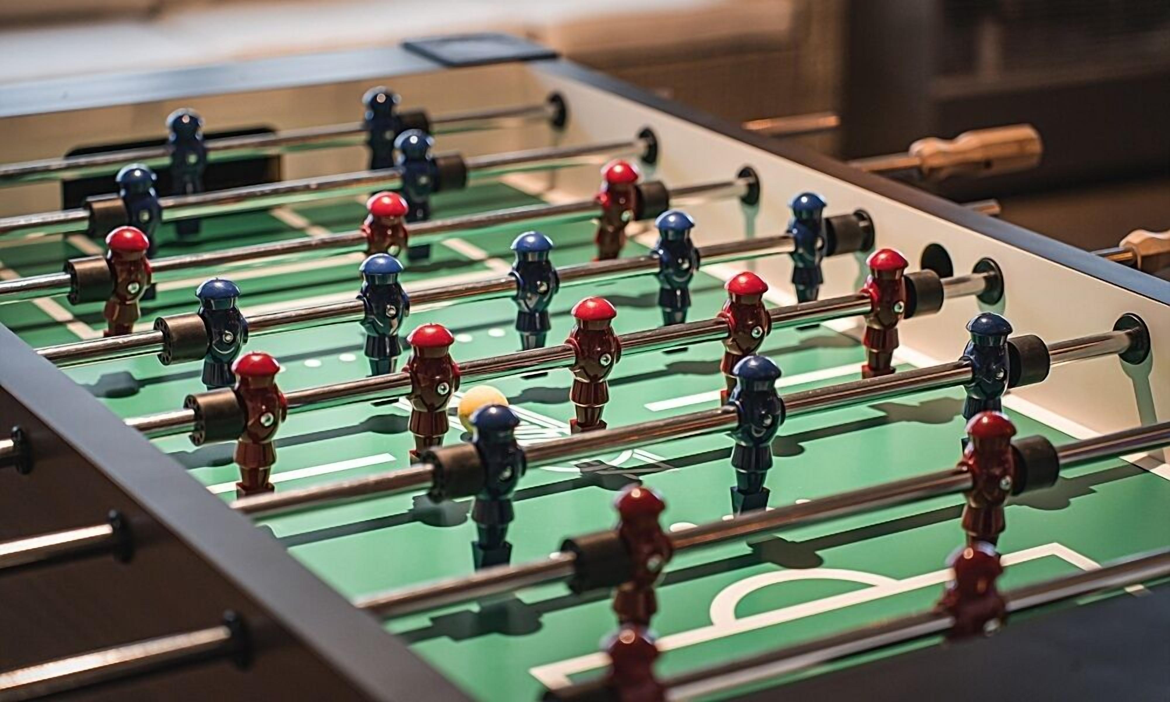 A close-up of a foosball table with multiple players and a ball.