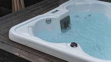 Un jacuzzi con panel de control y toma de corriente en una terraza de madera.