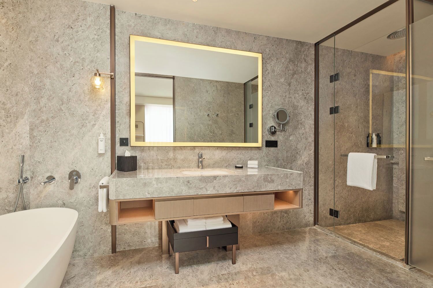 A modern bathroom with a large mirror, a bathtub, a shower, and a vanity with a sink and storage.