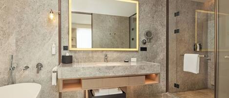 A modern bathroom with a large mirror, a bathtub, a shower, and a vanity with a sink and storage.