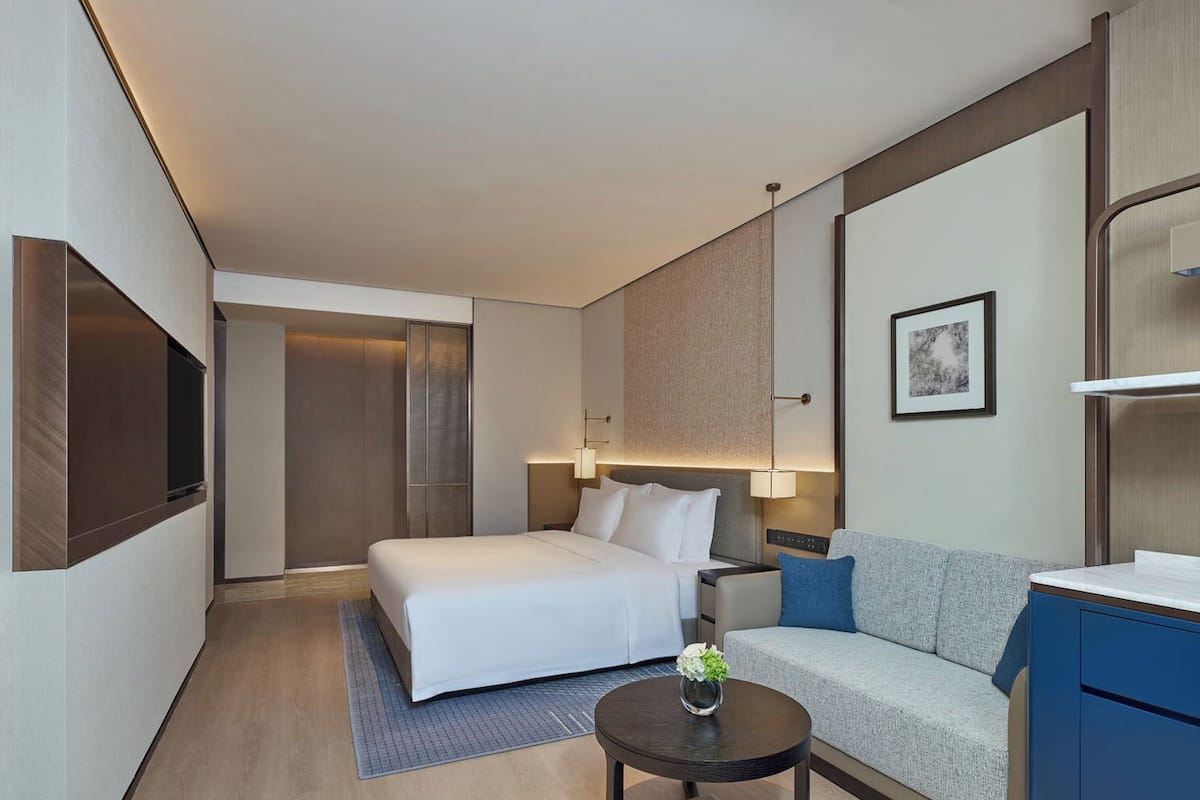 Une chambre d’hôtel moderne équipée d’un lit, d’un canapé, d’un bureau et d’une télévision.