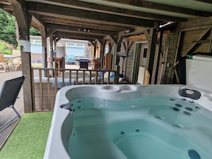 A hot tub under a wooden pergola with a view of a garden and outdoor seating area. - Studio 3B, The Carriage House. (Bilbrough)