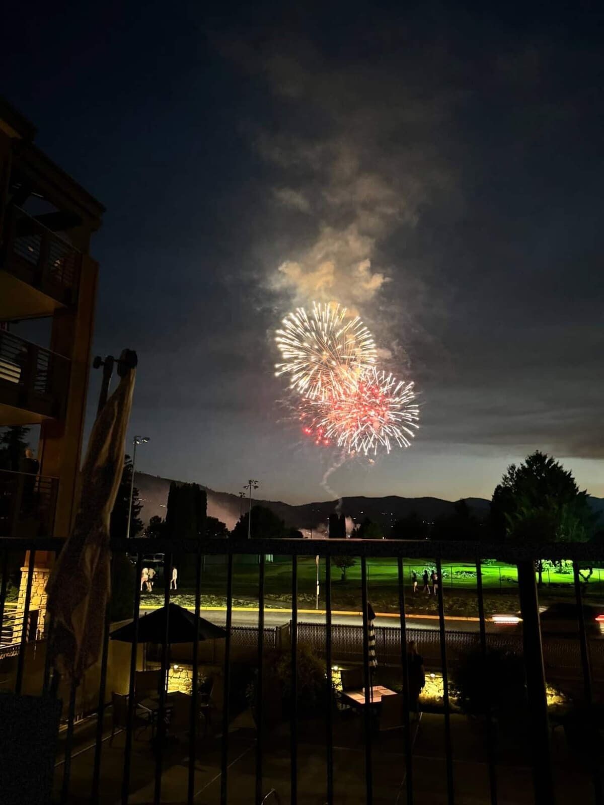 A nighttime view of a fireworks display over a residential area with a visible patio and outdoor seating area.