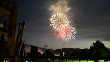 A nighttime view of a fireworks display over a residential area with a visible patio and outdoor seating area.