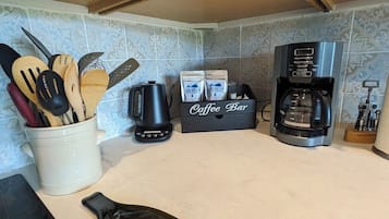 Et køkken med træskabe, en kaffemaskine, en kaffebar og en vinflaske.