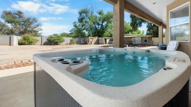 Ein Whirlpool mit Steinfassade, eine überdachte Terrasse und Blick auf eine Wohngegend.