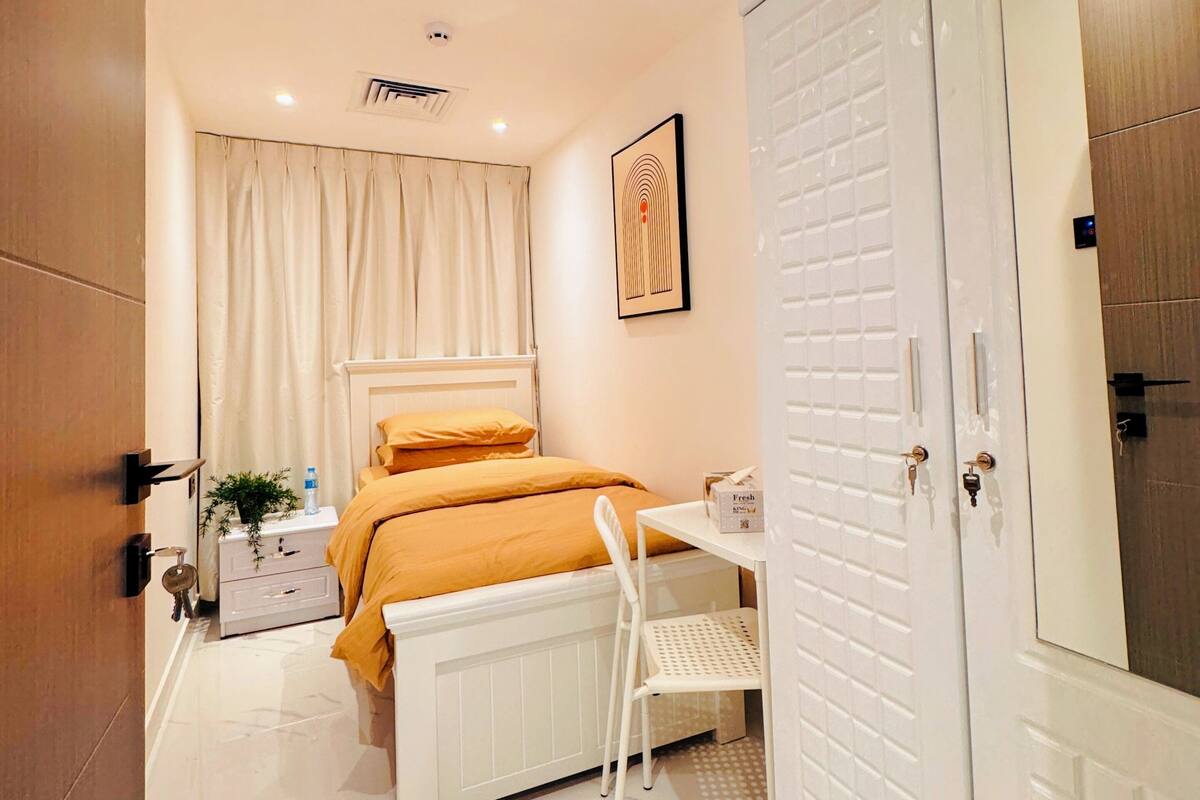 A bedroom with a bed, bedside table, and a wardrobe.