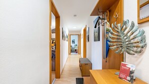 Een gang met houten vloer, een receptiebalie en een groot decoratief metalen blad aan de muur.