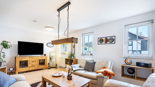 Een moderne woonkamer met een flatscreen televisie, houten meubels, een salontafel en een bank.