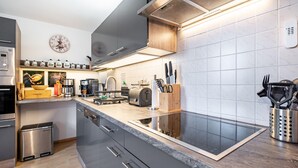 Een moderne keuken met een inbouwfornuis, roestvrijstalen apparatuur en een houten aanrecht.