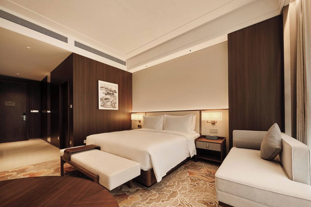 Habitación de hotel con una cama grande, un sofá, un escritorio y una silla.