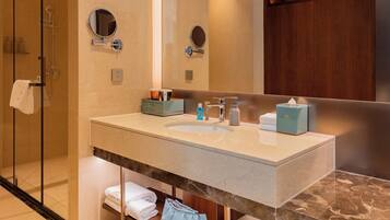 Un bagno con box doccia in vetro, lavabo con piano in marmo e specchio sopra il lavabo.