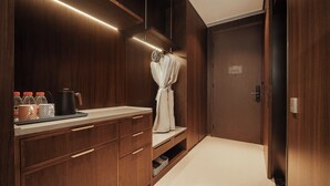 Un dressing avec des meubles en bois, une coiffeuse avec un miroir et un peignoir suspendu à un porte-manteau.