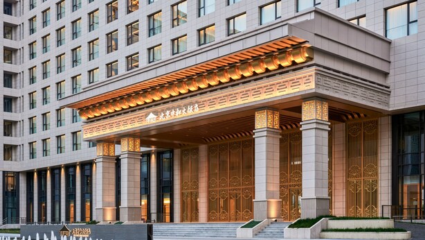 Un hôtel moderne doté d’une entrée imposante, avec une galerie couverte et des colonnes décoratives.