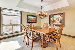 A dining room with a wooden table, six chairs, a chandelier, and two framed paintings. - Golf, Swim & Grill: Snowbird’s Escape in Sun Lakes (Sun Lakes)