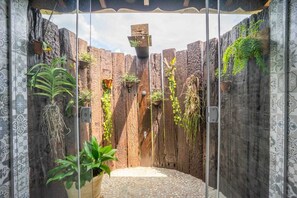 Une véranda fermée par des parois de verre, avec un mur en bois rustique, des plantes en pot et un sol carrelé.
