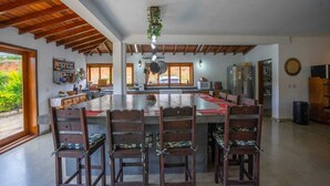 A spacious kitchen with a large island, wooden ceiling beams, and a view of the outdoors.