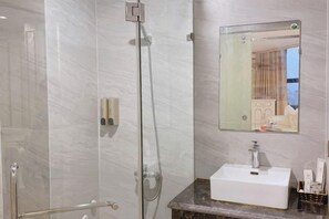 A modern bathroom with a glass-enclosed shower, a white sink, and a mirror above it. - KIM A HOTEL (Bac Ninh)