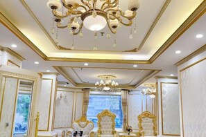 A luxurious room with a large chandelier, ornate gold detailing, and a large mirror. - KIM A HOTEL (Bac Ninh)