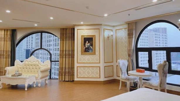 A spacious room with a large window, a white sofa, a small round table, and a bed.