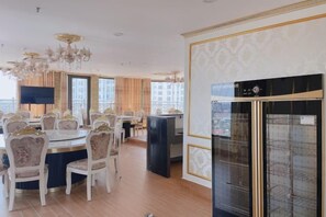 A hotel dining area with a round table, chairs, and a chandelier. - KIM A HOTEL (Bac Ninh)