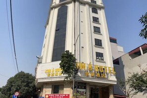 A hotel building with a prominent sign, multiple windows, and a clear sky. - KIM A HOTEL (Bac Ninh)