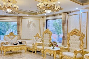 A luxurious room with ornate golden chairs, a chandelier, and large windows with curtains. - KIM A HOTEL (Bac Ninh)