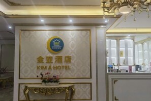 A reception area with a sign for Kim A Hotel, a decorative console table, and a chandelier. - KIM A HOTEL (Bac Ninh)