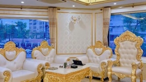 A luxurious room with ornate golden chairs, a white sofa, and a chandelier.