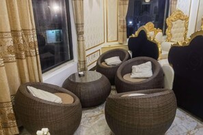 A room with round wicker sofas, a large window, and a mirror with ornate gold detailing. - KIM A HOTEL (Bac Ninh)