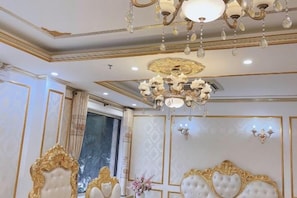 A luxurious room with ornate gold detailing, a chandelier, and a large bed with a white headboard. - KIM A HOTEL (Bac Ninh)