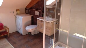 Een kleine badkamer met een wasmachine, toilet en douchecabine.