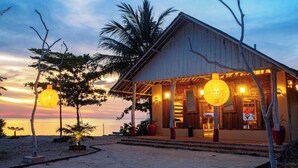 A beachside building with a covered porch and large spherical lights, overlooking the ocean. - Roka Resort by ARKasia Foundation (Bintan)