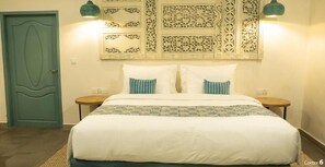 A bedroom with a bed, two nightstands, a door, and decorative wall panels. - Roka Resort by ARKasia Foundation (Bintan)