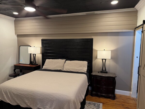 A bedroom with a bed, two bedside tables with lamps, a mirror, and a wooden headboard. - Renovated & Newly Refined~ w/Front porch & w/Back deck charm~ Scott/Lafayette (Lafayette)
