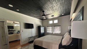 Ein Schlafzimmer mit einem großen Bett, einem Deckenventilator und einem an der Wand befestigten Fernseher.