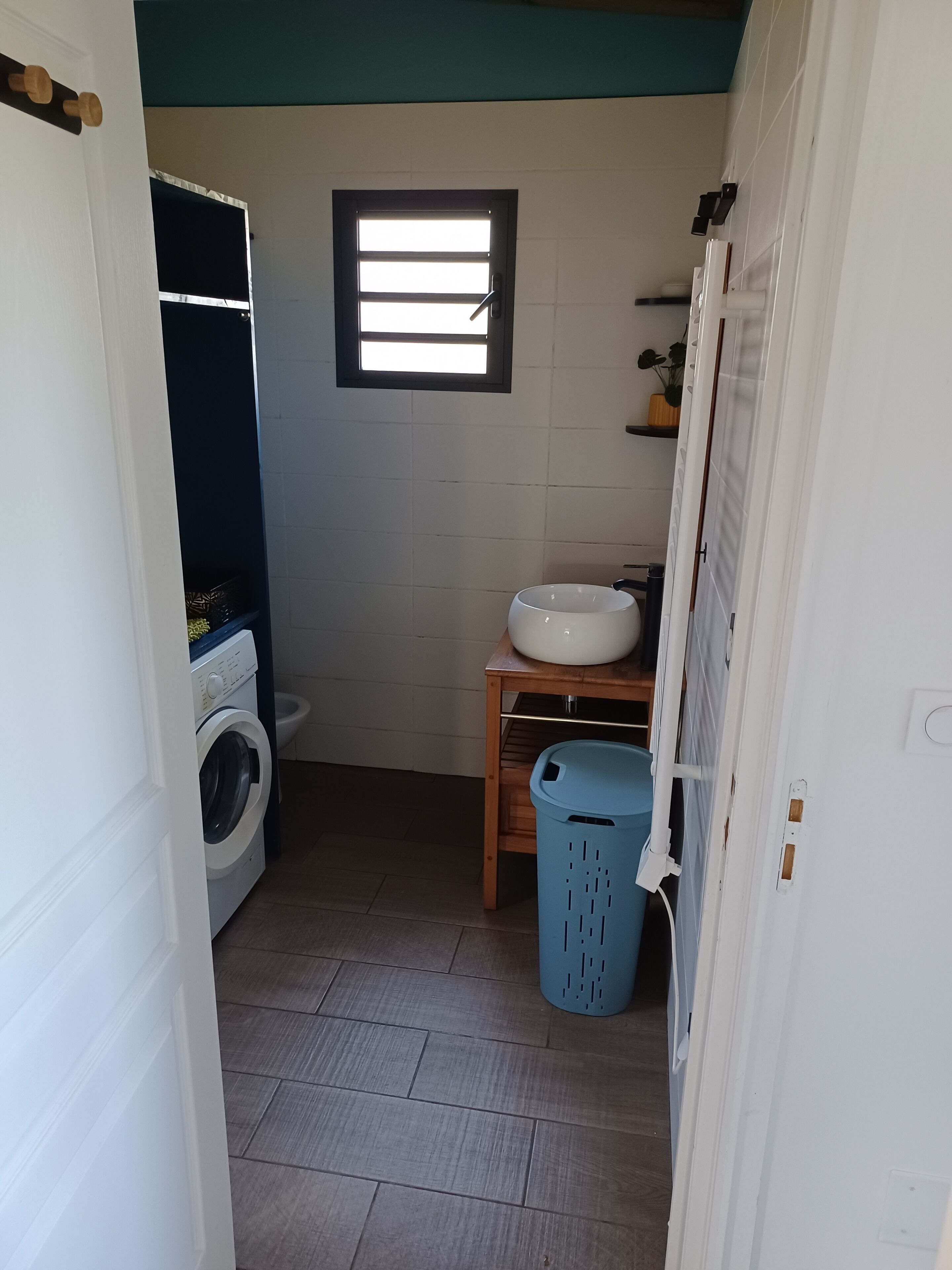 A compact bathroom with a washing machine, a sink, and a window.