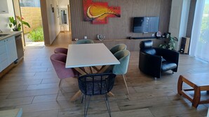 A modern living room with a white table, colorful chairs, a black sofa, and a TV on the wall. - Les trois songes Villa where partying is tolerated in the countryside  (Saint-Pierre)