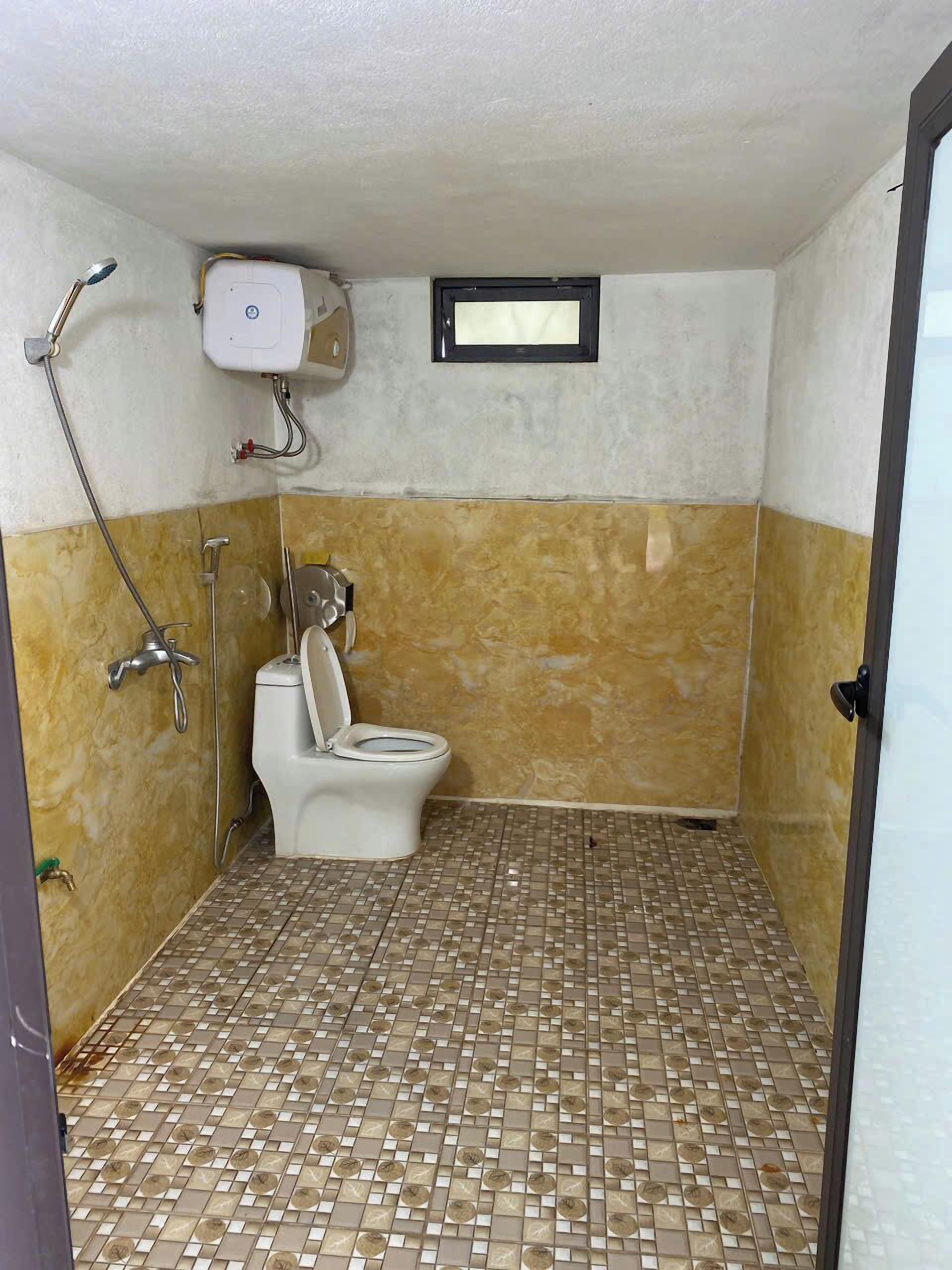 Um banheiro pequeno com azulejos, vaso sanitário, chuveiro e aquecedor de água instalado na parede.