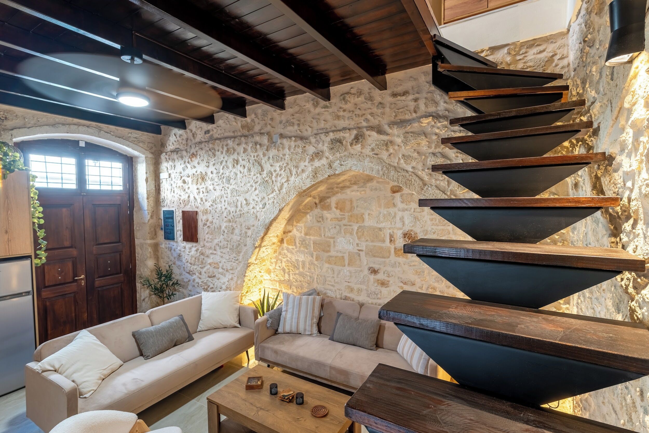 A cozy interior with a stone wall, wooden beams, a sofa, and a coffee table.
