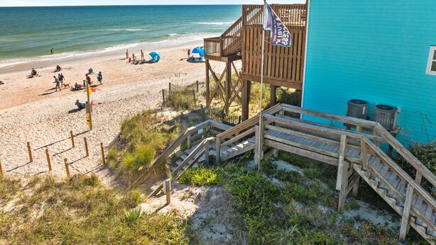 A beach with wooden walkways, a turquoise building, and beach umbrellas. - Safe Haven Cottage- Beach, Shopping, Fun! (Surf City)