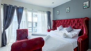 A bedroom with a large bed, a red armchair, and a view of the outdoors.