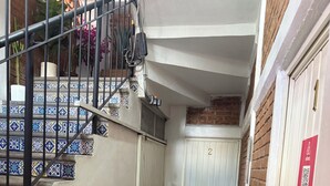 A narrow hallway with a tiled floor, a metal staircase with decorative tiles, a white door with a number, and a red fire extinguisher. - Beatiful aparment in the magical town of Orizaba 2 (Orizaba)