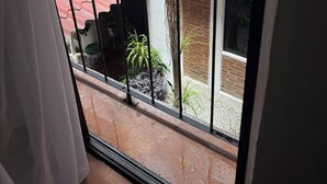A balcony with a red awning, potted plants, and a view of a brick building. - Beatiful aparment in the magical town of Orizaba 2 (Orizaba)