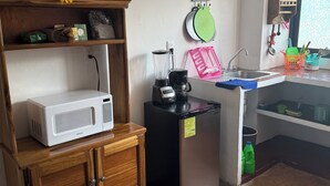 A compact kitchen with a microwave, refrigerator, and blender on a countertop. There is a shelf with decorative items and a window with a view. - Beatiful aparment in the magical town of Orizaba 2 (Orizaba)