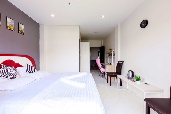A modern hotel room with a large bed, a desk, and a chair.