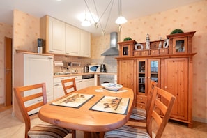 A kitchen with wooden cabinets, a dining table with chairs, and a microwave.