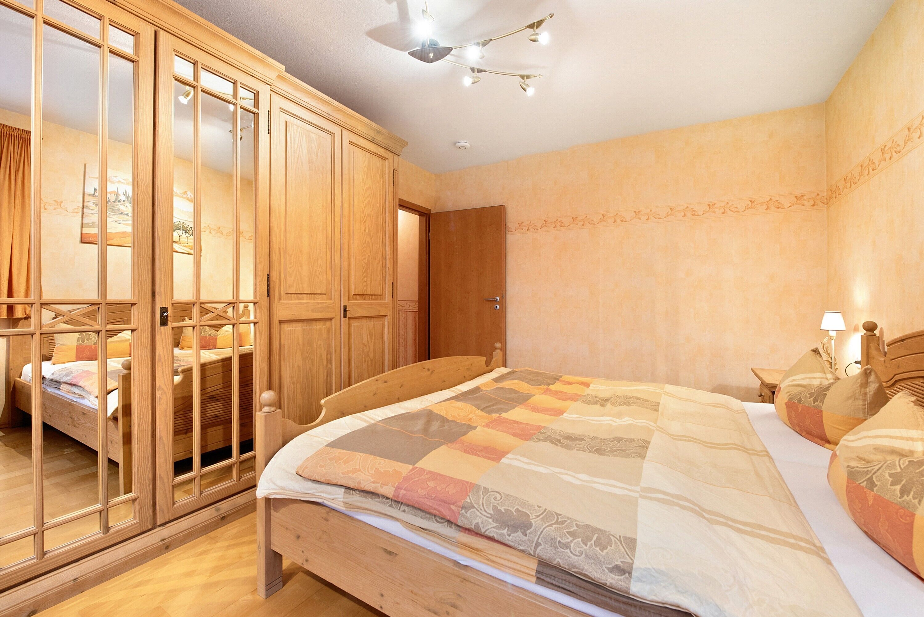 Un dormitorio con una cama de madera, un armario y un espejo.