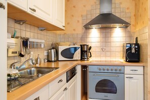Uma cozinha com forno embutido, cafeteira e micro-ondas.